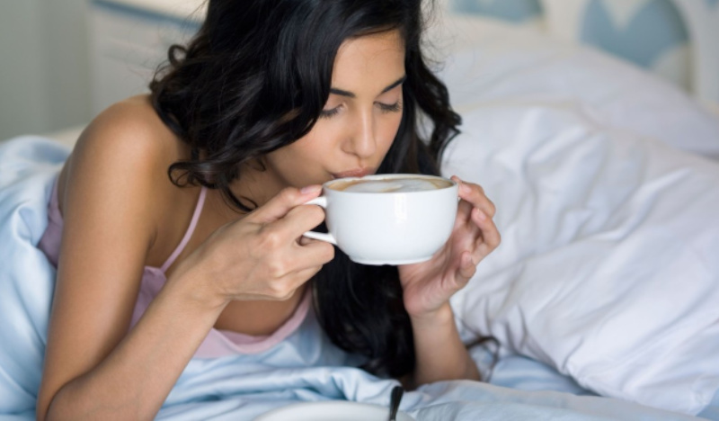 Девушка пьет кофе в кровати